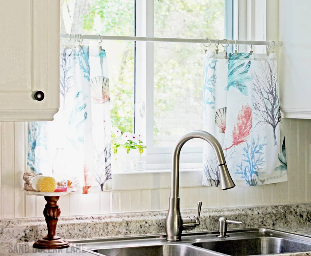 Cute Pottery Barn napkins make cute coastal style curtains in this pretty famhouse style kitchen