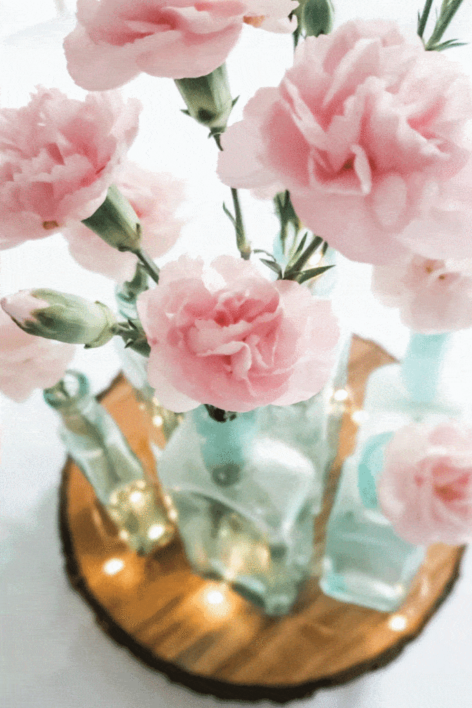 pink carnations in aqua medicine bottles for table centerpiece