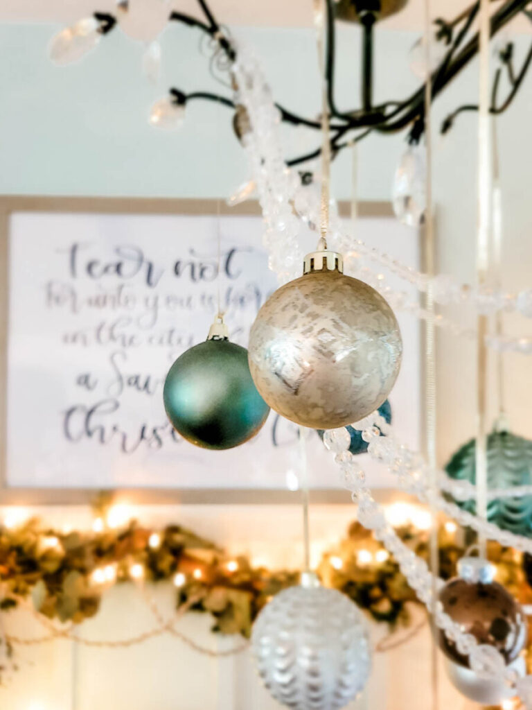 white and blue Christmas ornaments hanging from dining room chandelier